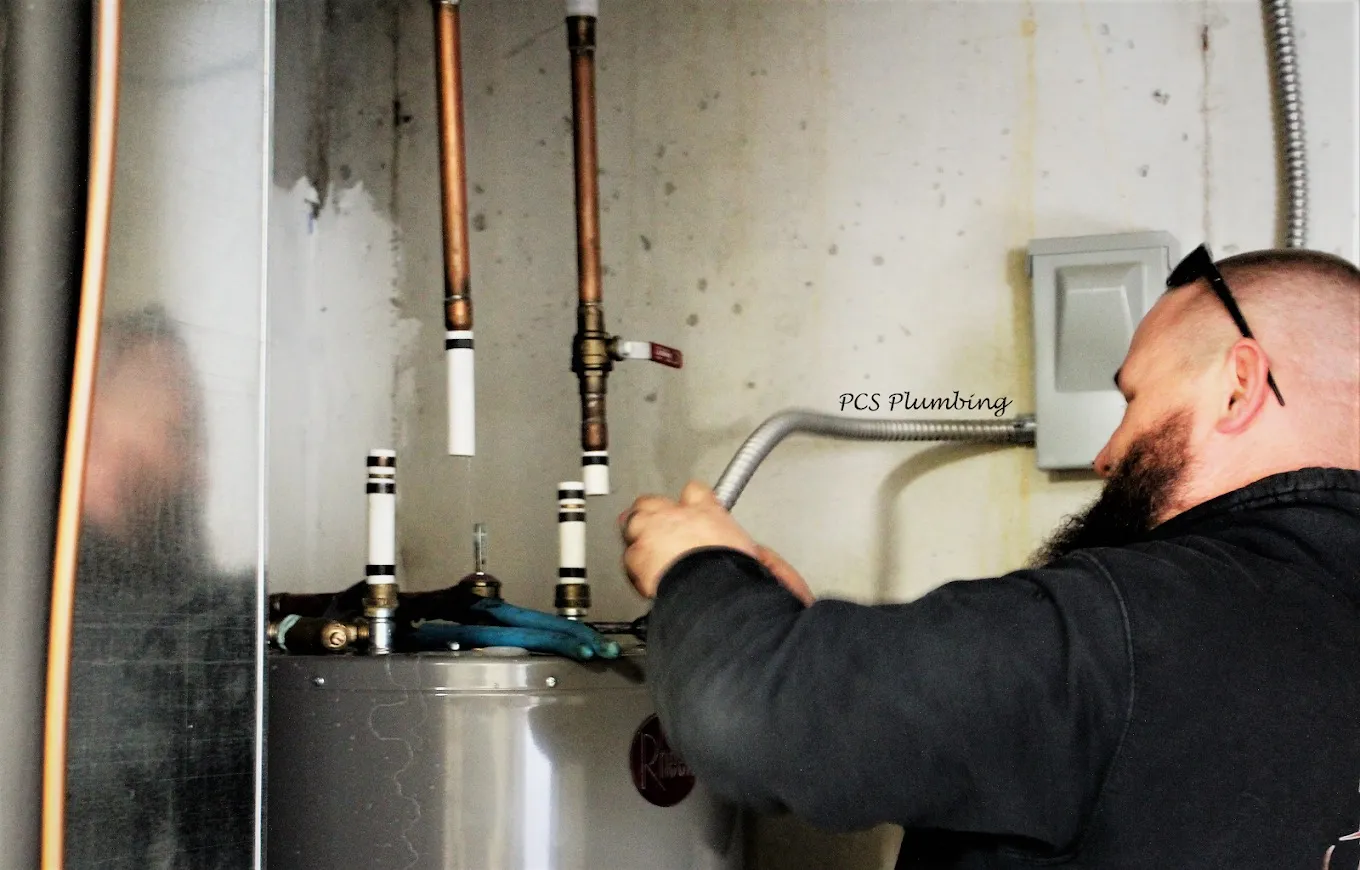 A PCS technician connecting a gas line to a water heater